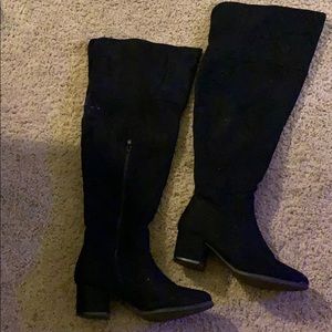 Thigh high black heeled boots.